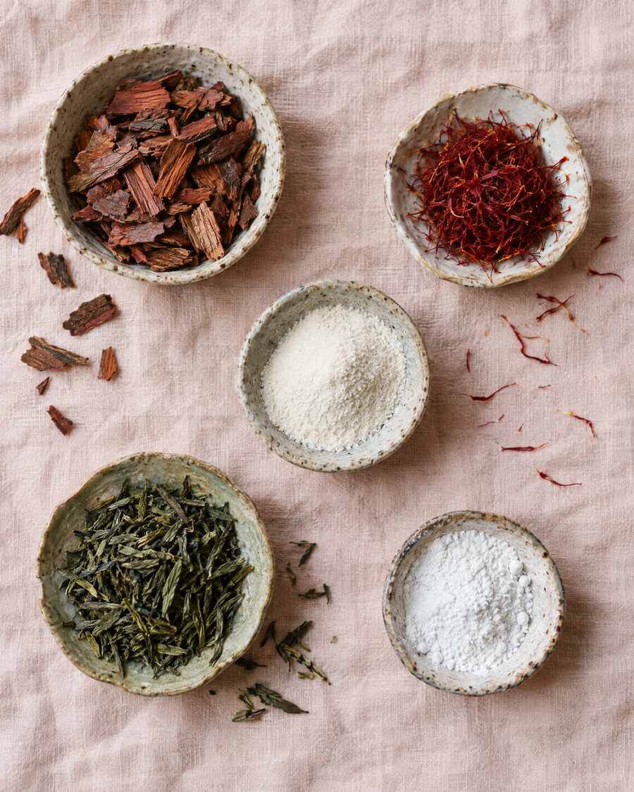 Pine bark, saffron threads, green tea and white powders in small ceramic bowls